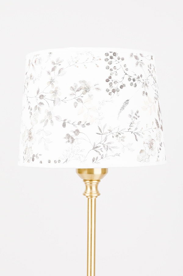 Elegant golvlampa med blommig lampskärm i vitt och guld, perfekt för att lysa upp och dekorera moderna hem.