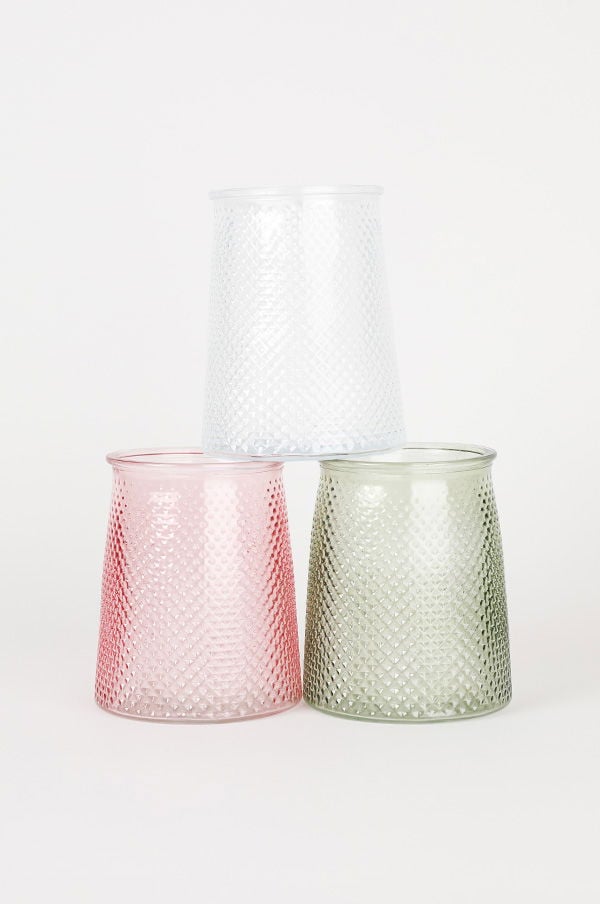 Tre färgglada glasbehållare i rosa, vitt och grönt, med en dekorativ mönstring, staplade på varandra. Perfekta för förvaring eller som dekorativa inslag i hemmet.