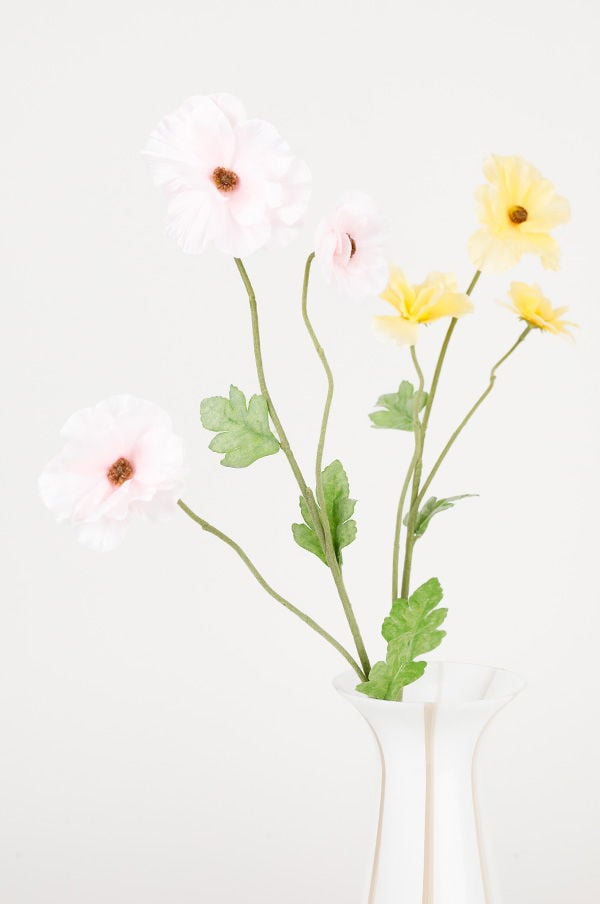 Vas med rosa och gula blommor i en ljus bakgrund, perfekt för inredning och dekoration.