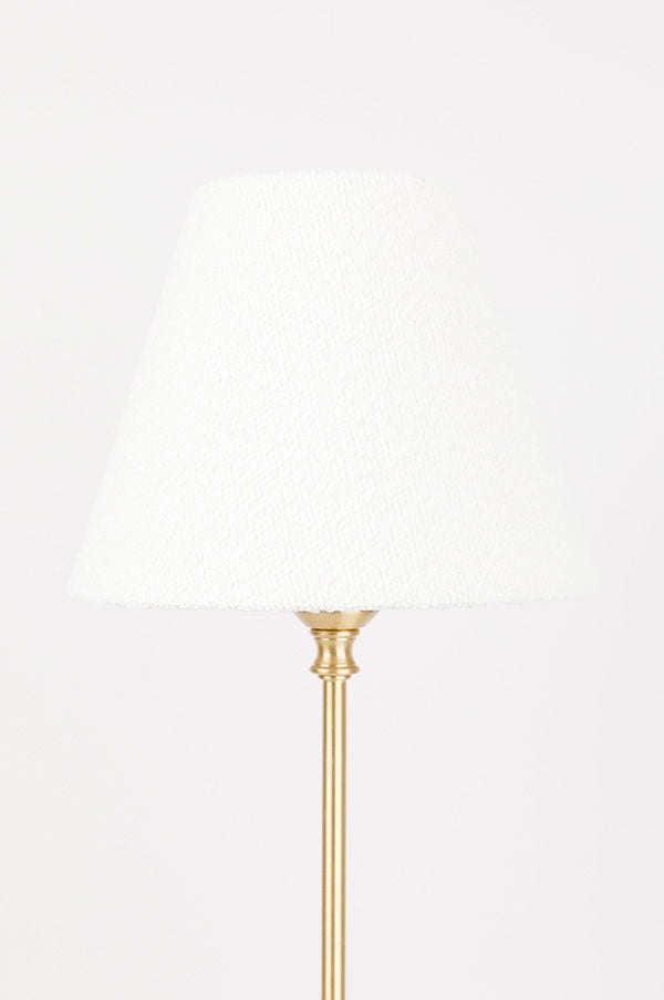 Vit lampskärm i textil på en elegant golvlampa med guldfärgad fot, perfekt för att skapa en varm atmosfär i hemmet.