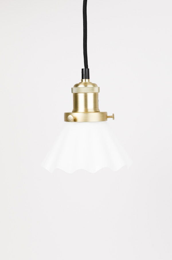 Hängande lampa med vit glasskärm och metallfäste i mässing, perfekt för att skapa en stilren och modern atmosfär i hemmet.