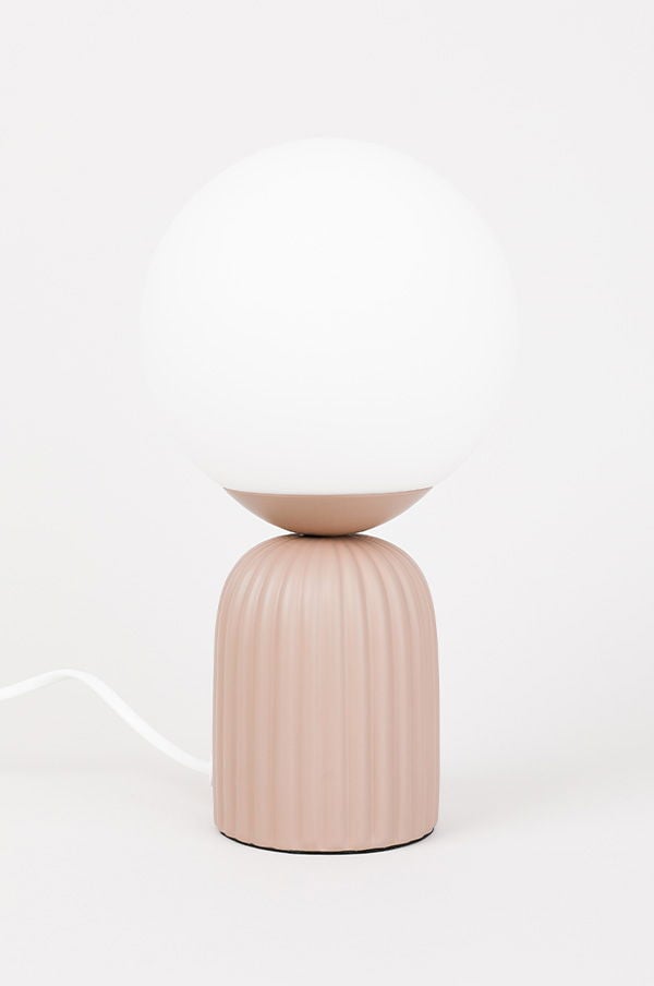 Söt bordslampa med rund vit glaskupa och en bas i mjuk, ribbad rosa färg. Perfekt för att skapa en mysig atmosfär i hemmet.