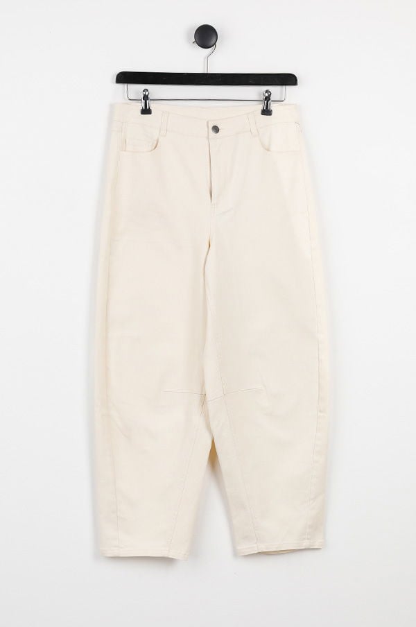 Ljusbeige byxor hängande på en svart klädhängare mot en vit bakgrund, perfekt för vår- och sommaroutfits.
