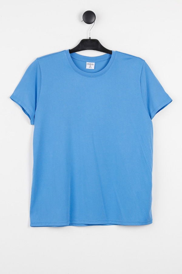 Blå t-shirt hängande på en svart klädhängare, enkel design med rundad halsringning, perfekt för vardagsbruk.