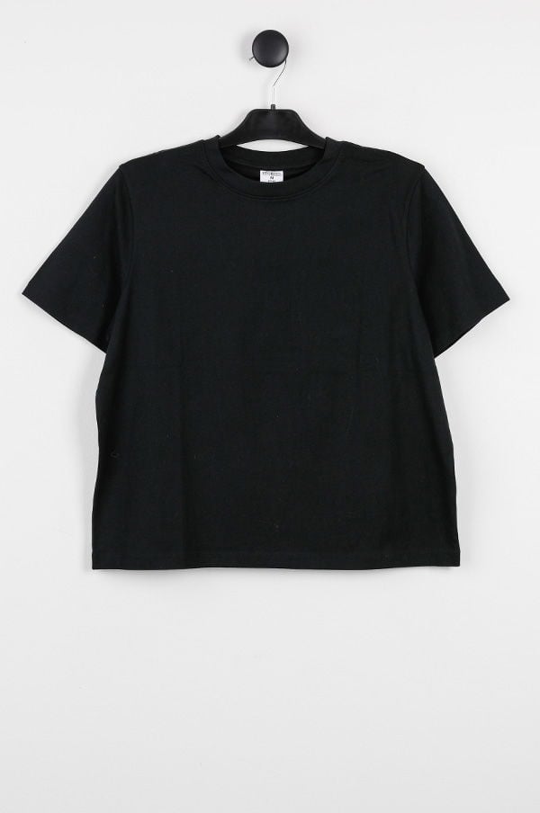 Svart t-shirt med kort ärm, hängande på en svart klädhängare mot en vit bakgrund. Perfekt för avslappnade outfits och vardagsbruk.