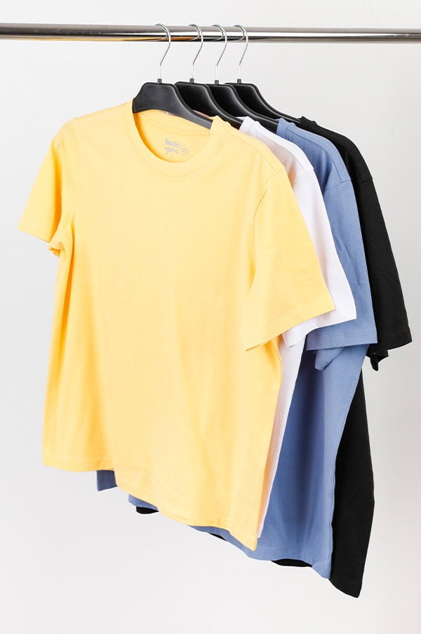 Flera t-shirts hängande på en klädhängare, inklusive färgerna gul, vit, blå och svart, som visar ett utbud av stiliga och mångsidiga kläder för vardagsbruk.