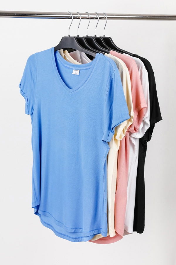 En uppsättning av fem t-shirts hängande på en klädhängare, inklusive färger som blå, beige, rosa, vit och svart. T-shirts har en avslappnad passform med V-hals. Perfekta för vardagsbruk och sommaroutfits.