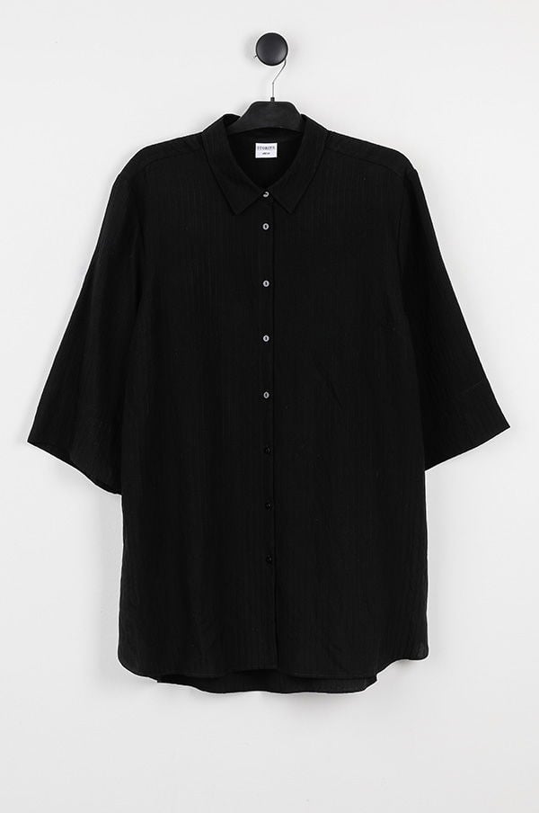 Svart skjorta med korta ärmar och krage, hängande på en klädhängare mot en vit bakgrund. Perfekt för en avslappnad, stilren look.