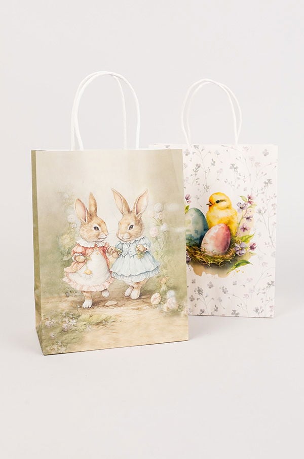 Två påskpåsar med illustrationer av kaniner och ett kycklingmotiv. Den vänstra påsen visar två kaniner i klänningar som håller händerna, medan den högra påsen har en kyckling och färgglada ägg i ett bo. Perfekt för påskpresenter och dekoration.