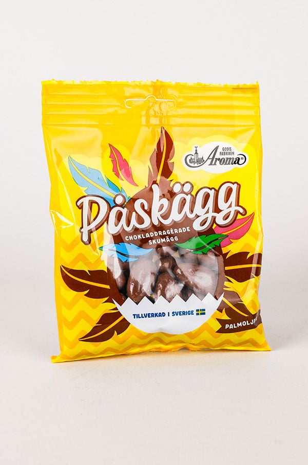 Påsen med Paskägg innehåller chokladdragna skumägg, tillverkade i Sverige. Förpackningen har en färgglad design med gula och gröna inslag, perfekt för påskfirandet.