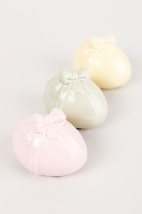 Tre keramiska ägg i pastellfärger med rosett, rosa, grön och gul, perfekt för påskdekoration eller som stiliga inredningsdetaljer.