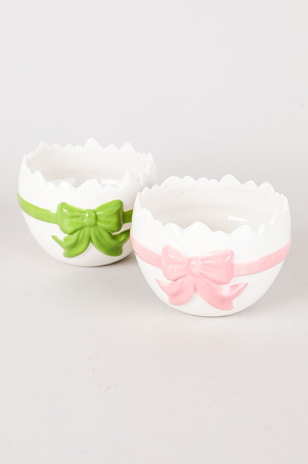 Två dekorativa skålar i keramik med färgglada band, en grön och en rosa, på en ljus bakgrund. Skålarna har en unik äggformad design med en flikig kant. Perfekta för att förvara småsaker eller som dekoration.