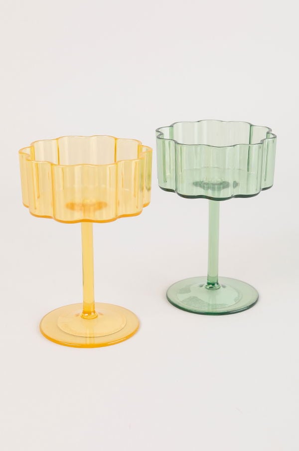 Färgglada glas i plast, ett gult och ett grönt, med vågiga kanter och stiliga fotar. Perfekta för festligheter och inredning.