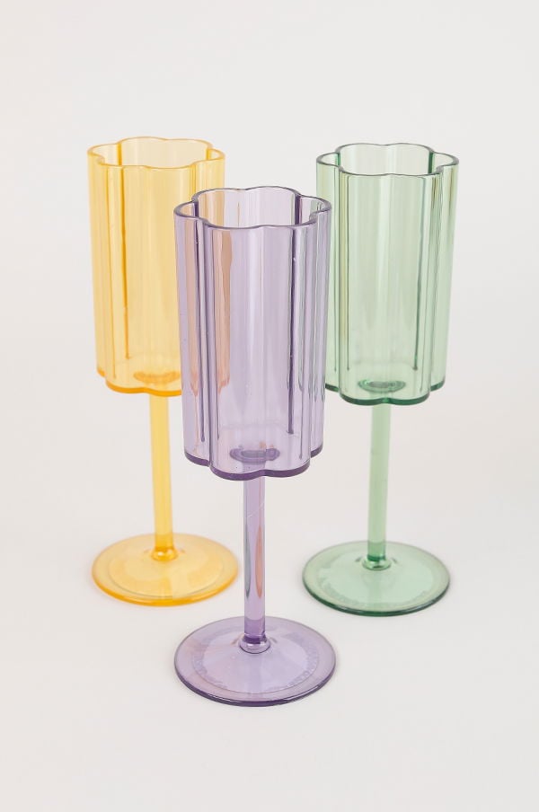 Färgglada plastglas i gult, lila och grönt med blommig kant, perfekta för festliga tillfällen och utomhusevenemang.