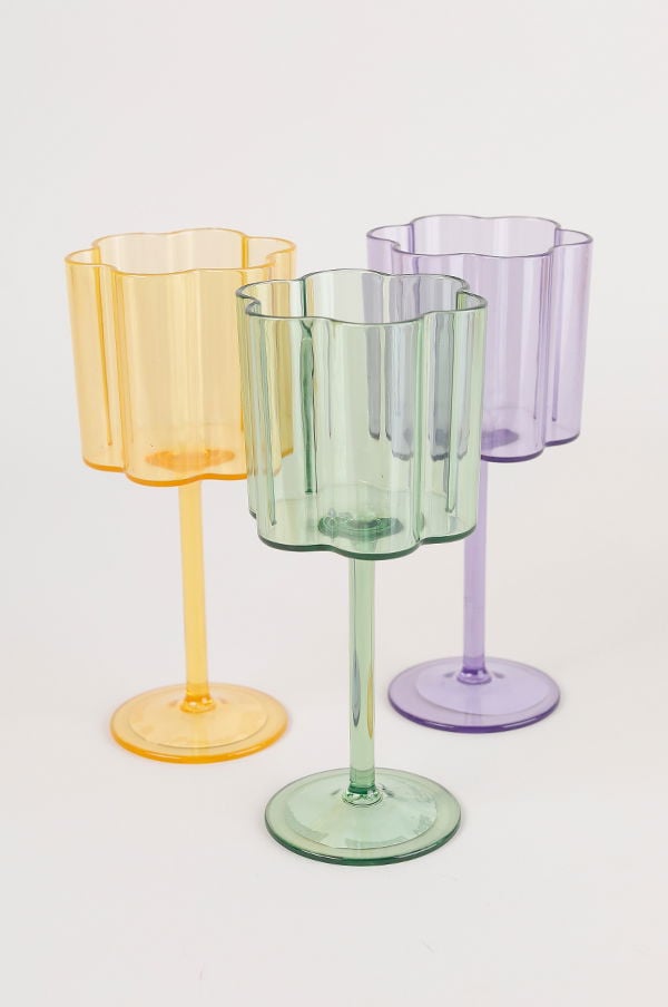 Färgglada plastglas i tre olika nyanser: gult, grönt och lila, med en elegant, vågig design och stiliga fotar. Perfekta för festliga tillfällen och dekoration.