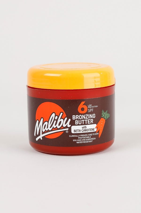 Malibu bronzing butter med SPF 6 i en röd burk, berikad med beta-karoten för att ge en solbrun hudton och skydd mot UV-strålar.
