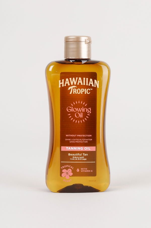 Flaska med Hawaiian Tropic Glowing Oil, ett solbrunande olja utan skydd, som ger en vacker solbränna. Innehåller vitamin E och har en tropisk doft. Perfekt för att få en gyllene hudton.