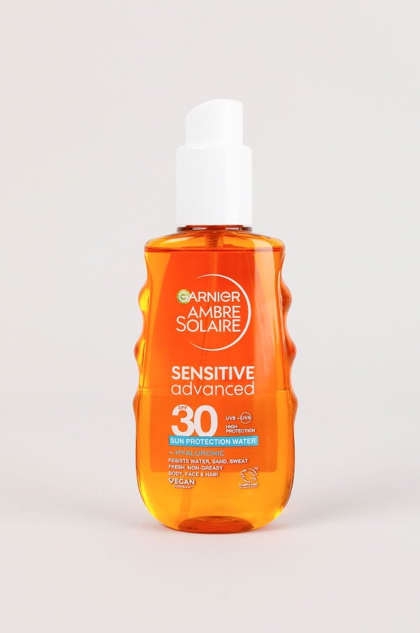 Flaska med Garnier Ambre Solaire Sensitive Advanced solskyddsvatten med SPF 30, designad för att skydda huden mot UV-strålar. Innehåller hyaluronsyra och är vattenresistent, icke-fet och lämplig för kropp, ansikte och hår. Veganvänlig produkt.
