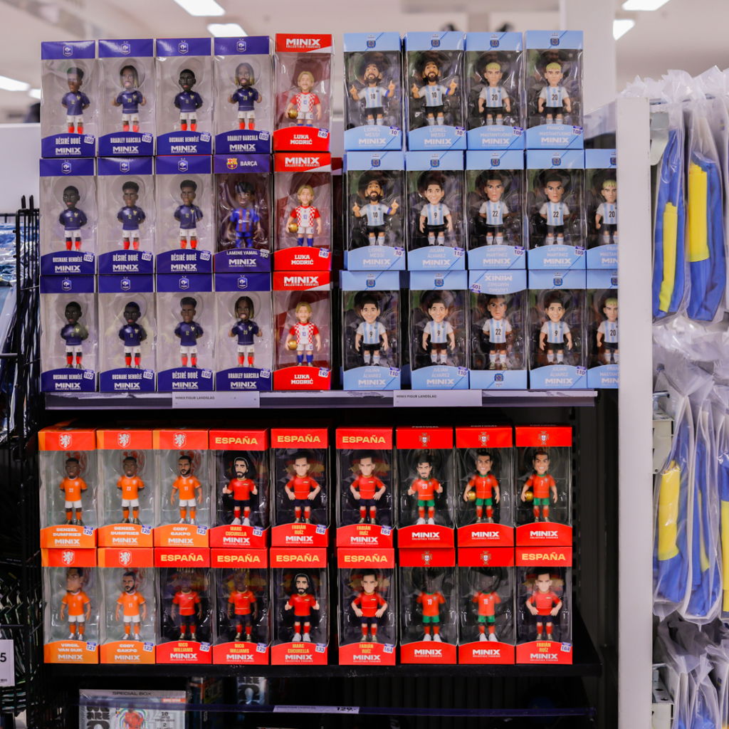 Samling av fotbollsfigurer i plast, inklusive spelare från olika lag som Argentina, Spanien och Kroatien, utställda på hyllor i en butik.