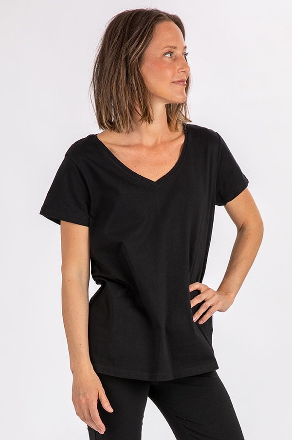 Svart t-shirt med V-ringning, bärs av en kvinna med kort brunt hår, i en enkel och stilren pose. Perfekt för avslappnade och vardagliga outfits.