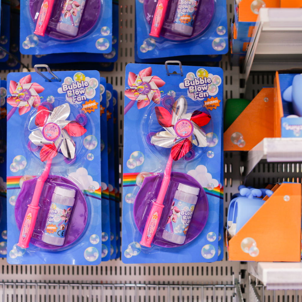 Bild på en förpackning med en bubblblåsare och tillhörande såpbubbelflaska. Produkten har en färgglad design med en blomformad fläkt och är placerad på en hylla i en butik.