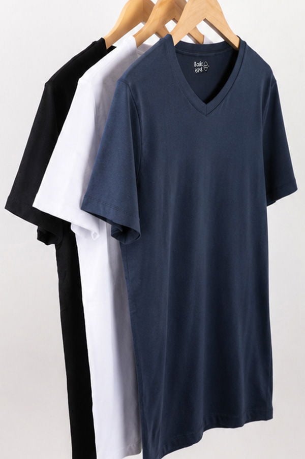 Tre T-shirts i olika färger hängande på trägalgar: svart, vit och marinblå, med V-halsdesign. Perfekta för en avslappnad stil.