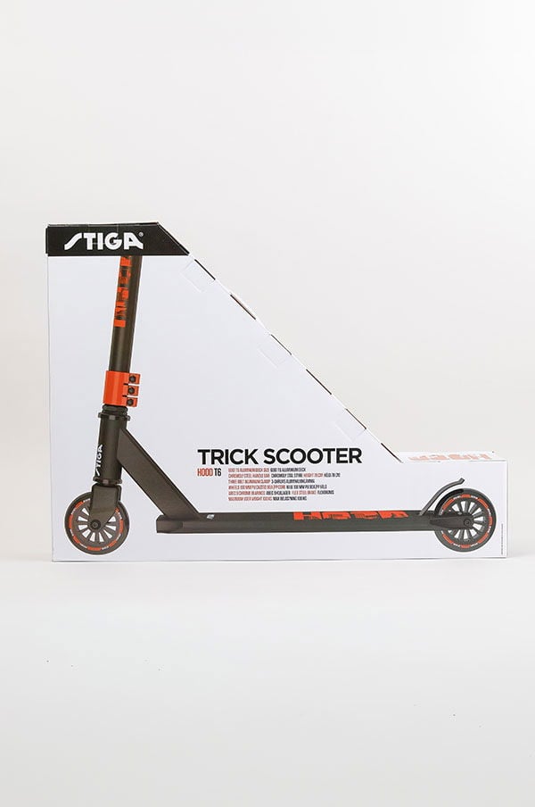 Trick scooter från STIGA, modell Hood T6, förpackad i en vit och svart låda med orange detaljer.
