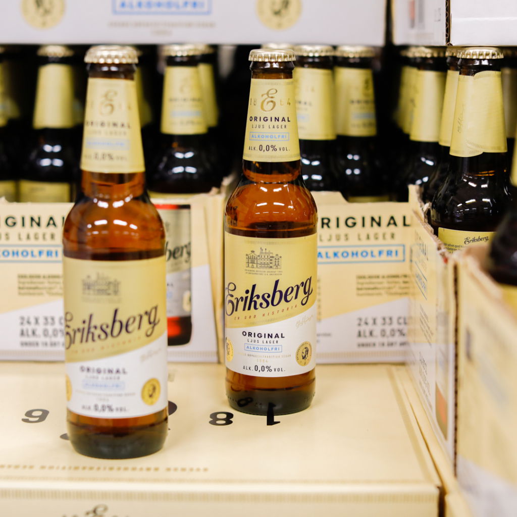 Flaskor med Eriksberg Original Ljus Lager, alkoholfri öl med 0,0% alkohol, placerade på hyllor i en butik.