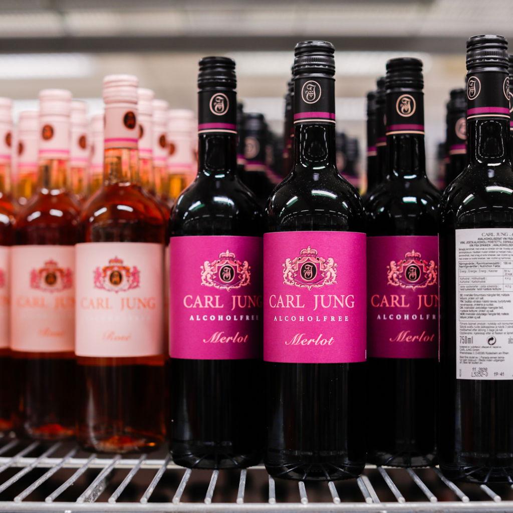 Flaskor med alkoholfria viner från Carl Jung, inklusive Merlot och Rosé, på hyllan i en butik.
