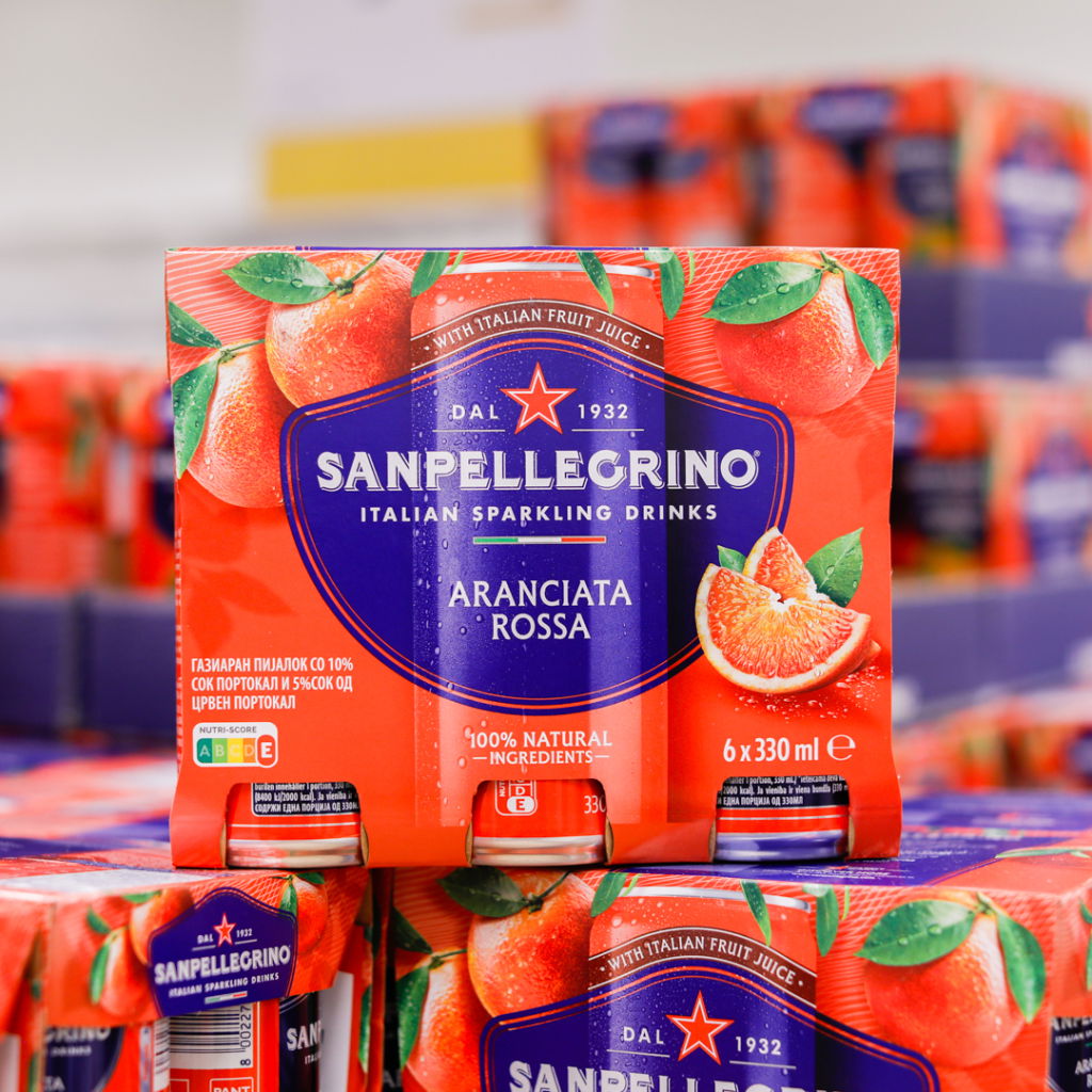 Sanpellegrino Aranciata Rossa, italiensk kolsyrad dryck med apelsinjuice, förpackning med sex burkar à 330 ml, 100% naturliga ingredienser, synlig på hylla i butik.