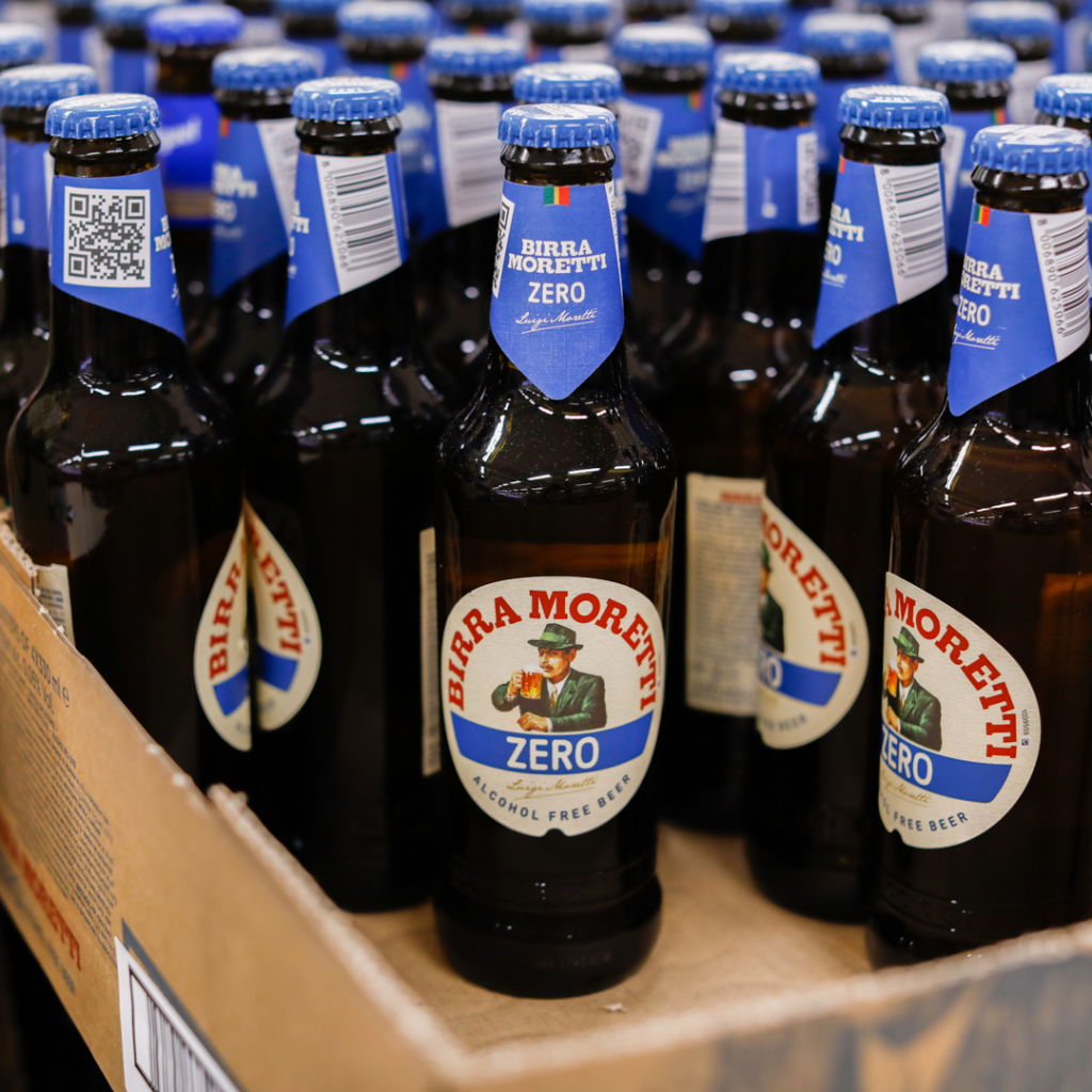 Flaskor med Birra Moretti Zero, alkoholfri öl, placerade i en kartong. Flaskorna har blå kapsyler och etiketter med information om produkten.