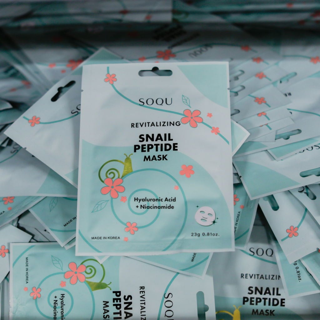 Förpackningar av SOQU Snail Peptide Mask, en revitaliserande ansiktsmask med hyaluronsyra och niacinamid, designad för att återfukta och förbättra hudens struktur. Maskerna är tillverkade i Korea.