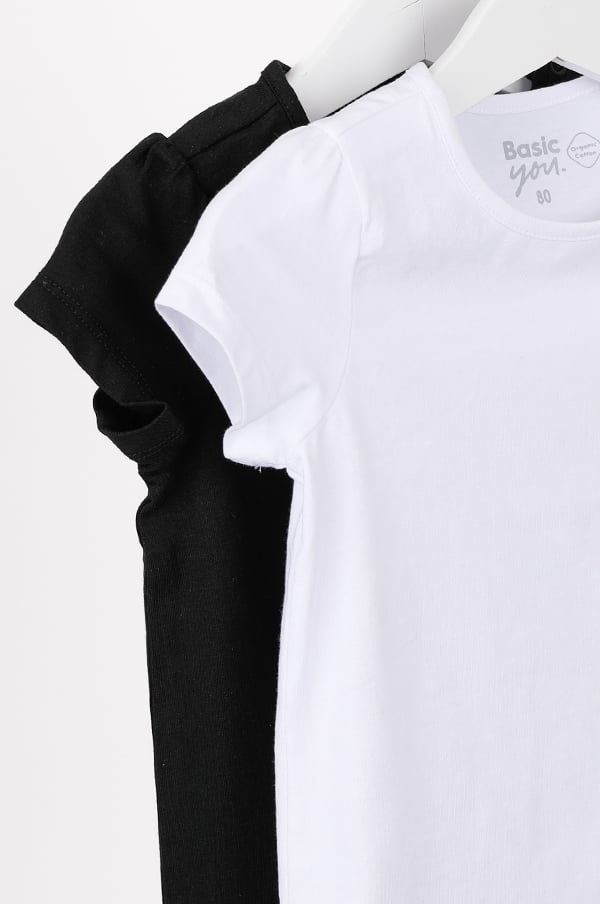 Två t-shirts i svart och vitt, med korta ärmar, hängande på en klädhängare. T-shirtsen är av märket Basic You och storlek 80, perfekta för barn.