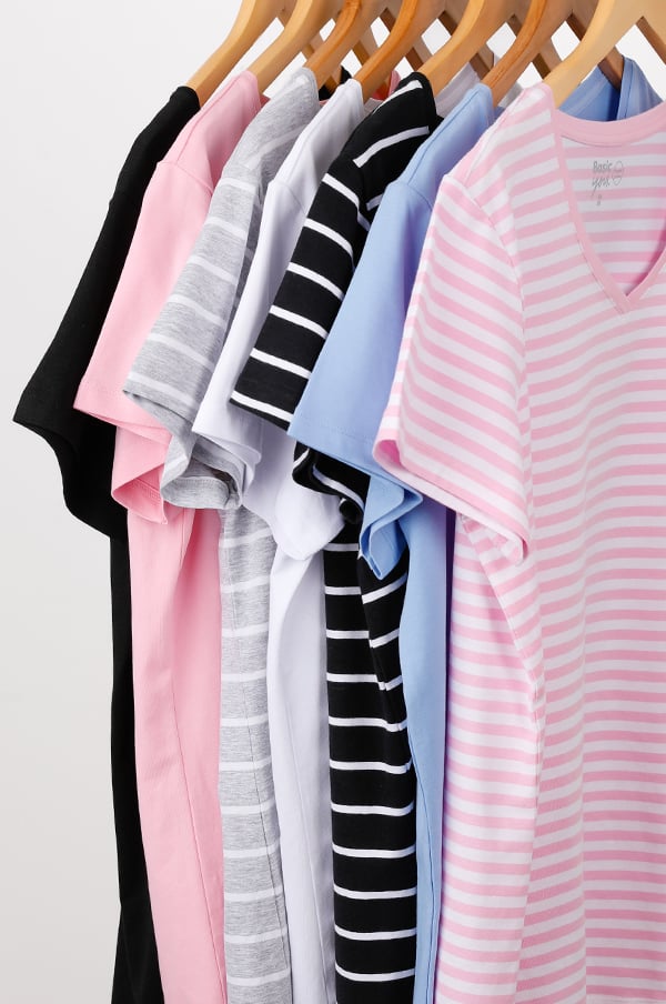 Flera t-shirts i olika färger och mönster hängande på klädhängare, inklusive svart, rosa, grå, vit och randig design.