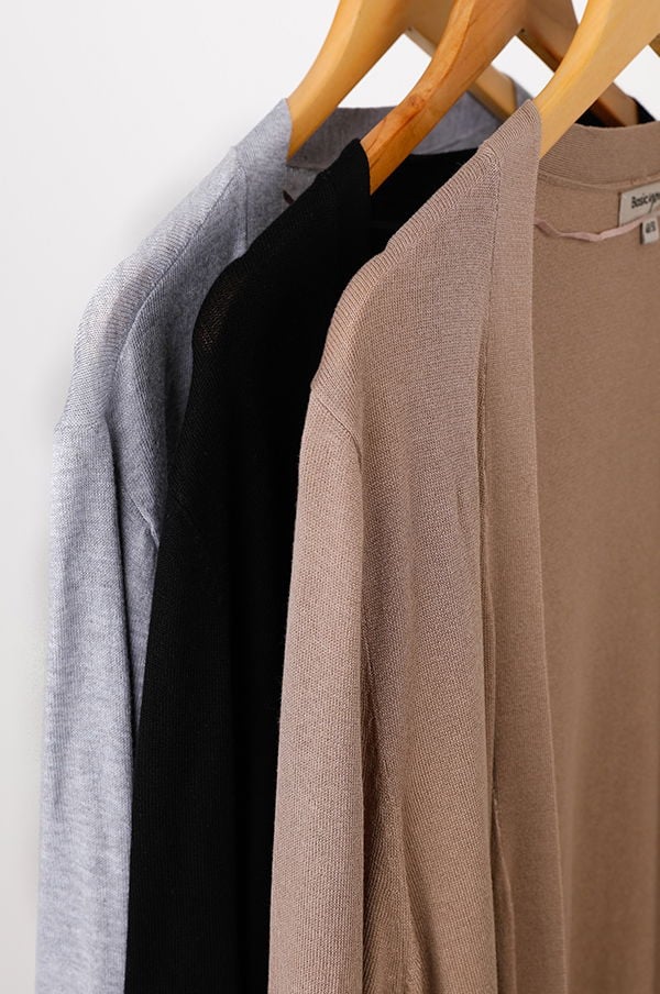 Tre färgade koftor hängande på galgar, i nyanserna grå, svart och beige, perfekt för stiliga och bekväma outfits.