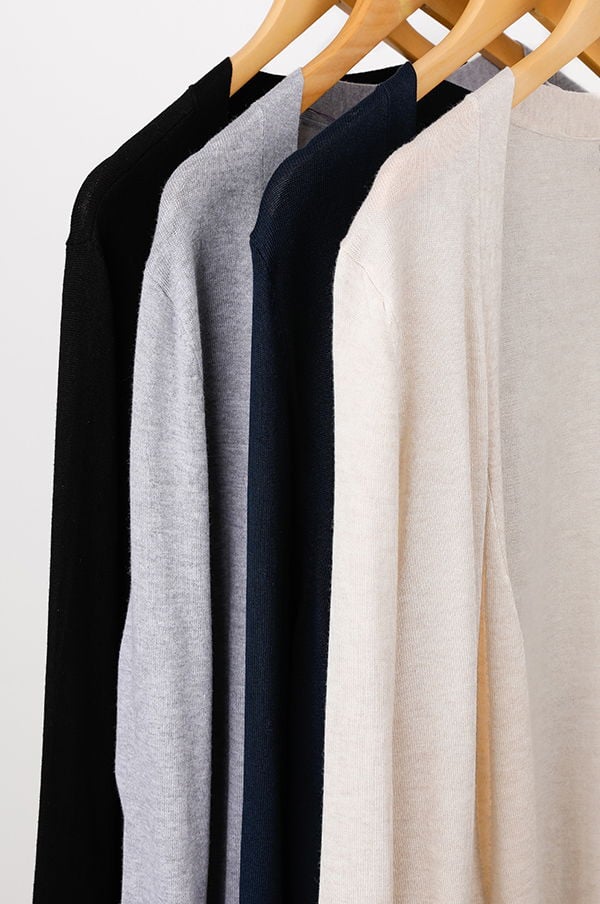 Flera tröjor i olika färger hängande på galgar, inklusive svart, grå, marinblå och beige, perfekt för stiliga och bekväma outfits.