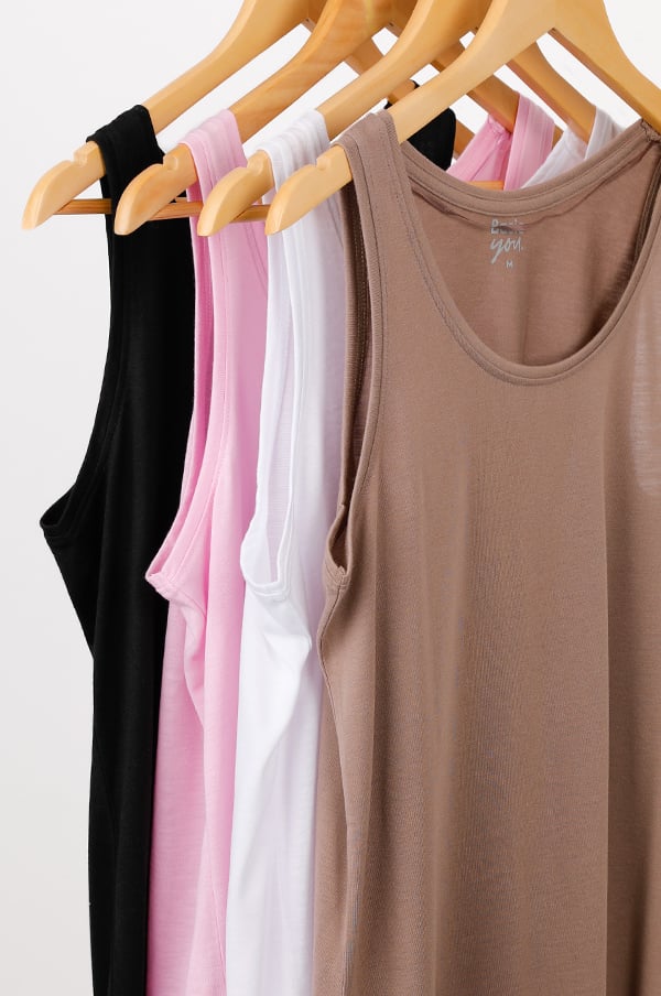 Flera tanktops i olika färger hängande på klädhängare, inklusive svart, rosa, vit och brun. Perfekta för både vardagsbruk och träning.