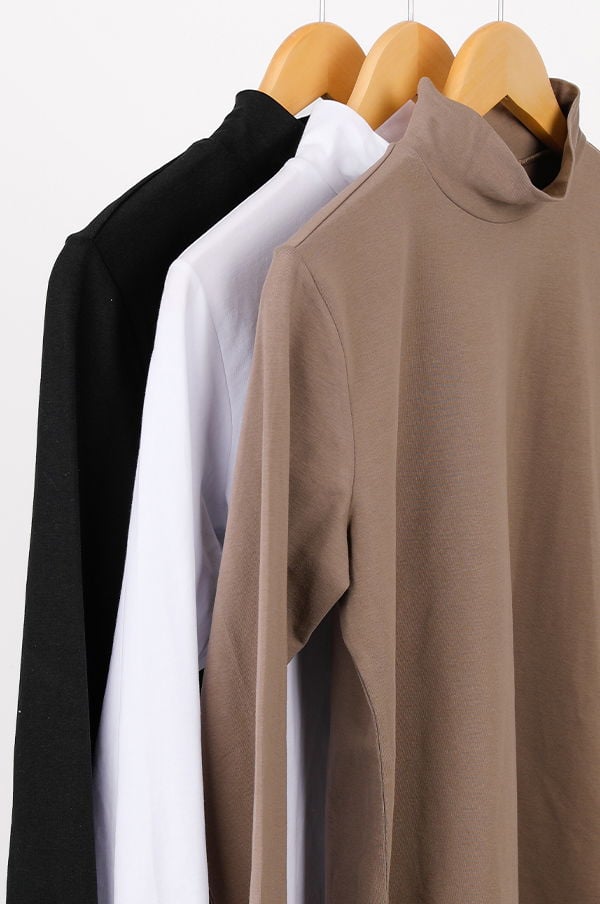 Tre långärmade tröjor i svart, vitt och beige hänger på klädhängare. Tröjorna har en modern design med hög krage, perfekta för både vardag och fest.