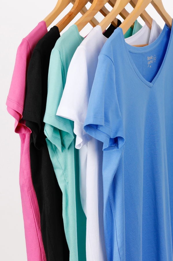 Flera färgglada t-shirts hängande på en trägalge, inklusive rosa, svart, mintgrön, vit och blå, med fokus på v-ringning och mjukt material. Perfekt för casual stil och sommartemperaturer.