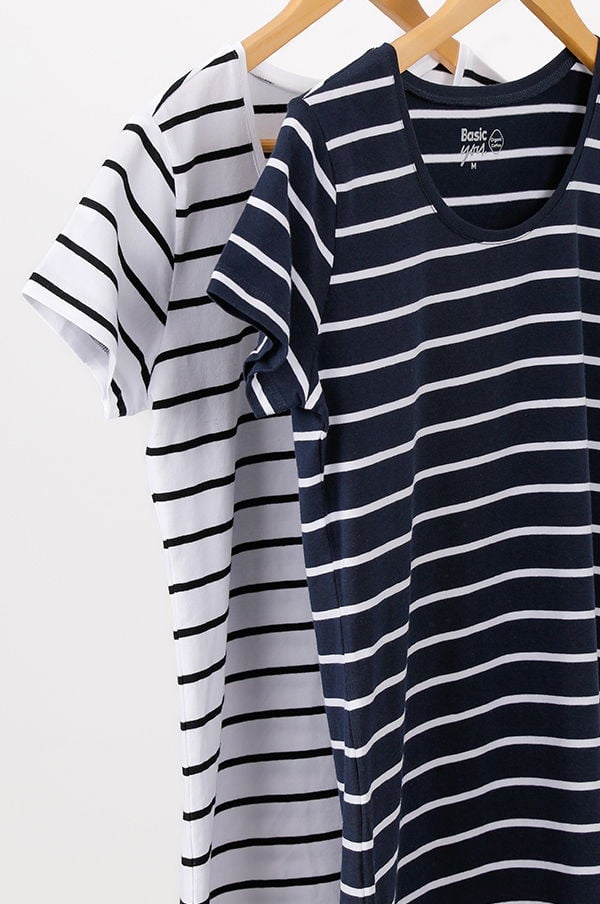 Två randiga t-shirts hängande på en klädhängare, en vit med svarta ränder och en marinblå med ljusgrå ränder, i en enkel och stilren design.