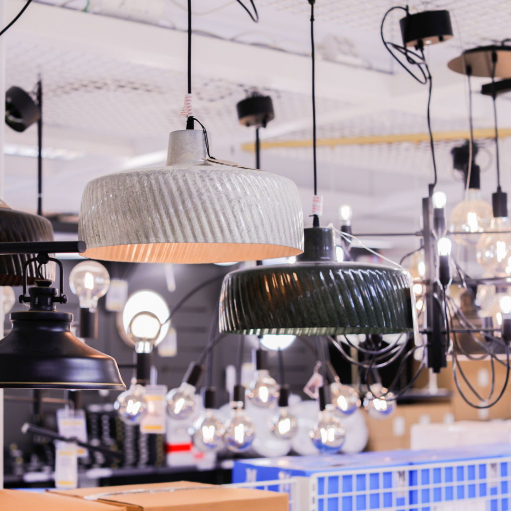 Hängande lampor i olika stilar och färger i en belysningsbutik, med fokus på moderna och industriella designalternativ.