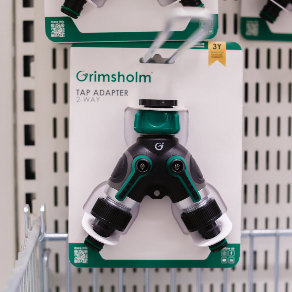 Tapadapter 2-vägs från Grimsholm, designad för att ansluta två slangar till en kran, praktisk för trädgårdsarbete och bevattning.