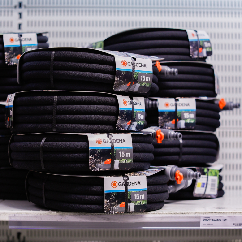 Förpackningar med Gardena droppslang, 15 meter, staplade på en hylla i en butik.