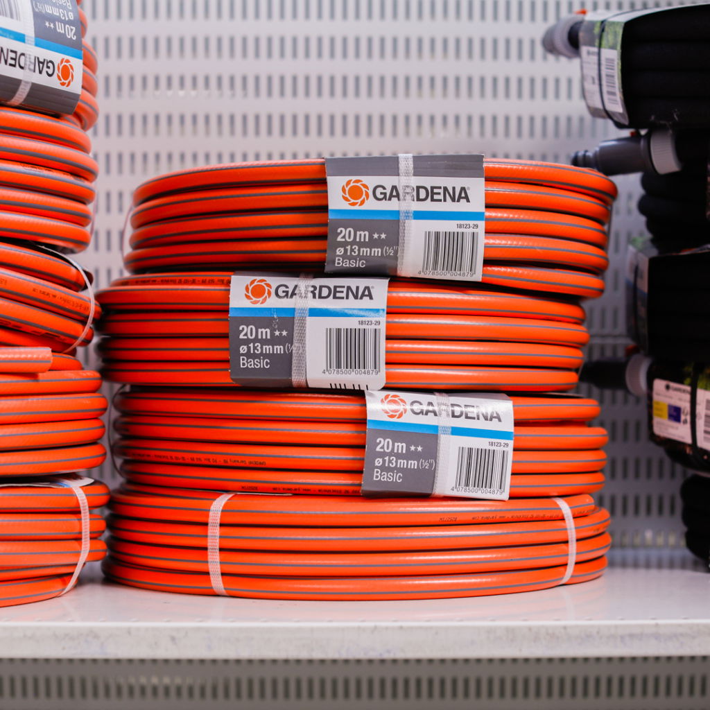 Rulle av Gardena vattenslang, 20 meter lång och 13 mm i diameter, staplad på en hylla i en butik.