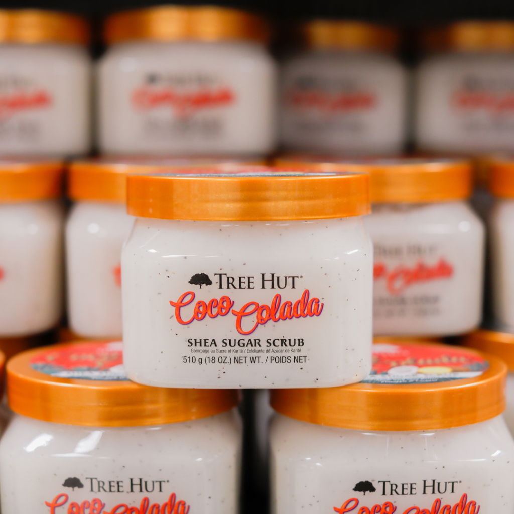 Burk med Tree Hut Coco Colada sheasmörsskrubb, 510 g, med orange lock och vit krämig konsistens, placerad bland andra liknande produkter.