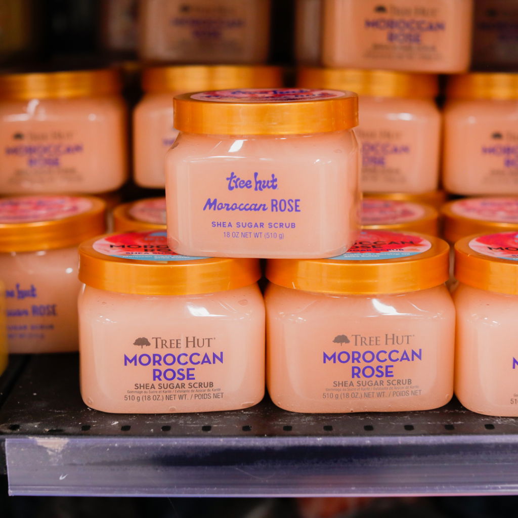 Burkar med Tree Hut Moroccan Rose shea socker skrubb på hyllan, varje burk har en orange lock och innehåller 510 g. Produkten är populär för sin återfuktande och exfolierande effekt.