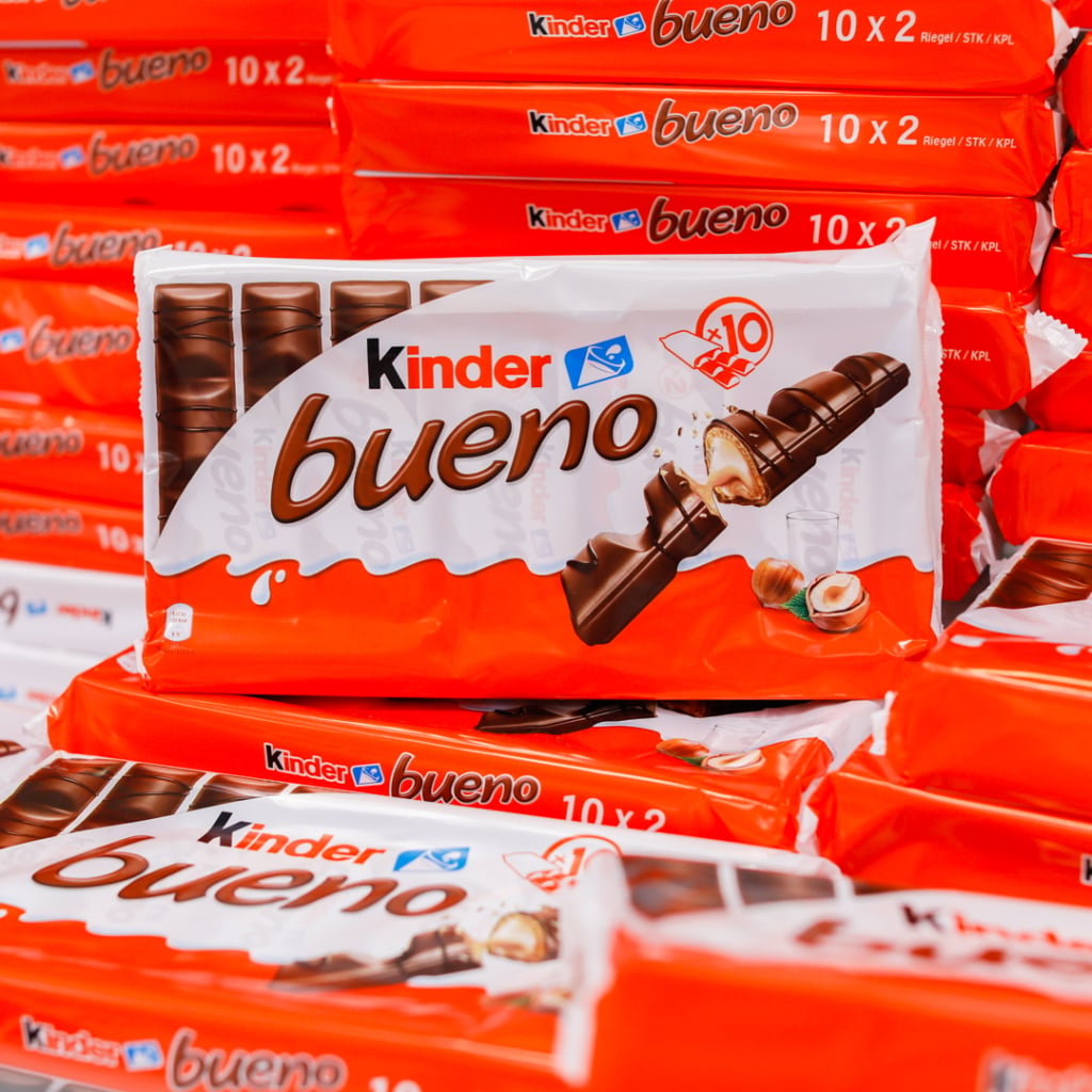 Förpackning av Kinder Bueno med flera rader av chokladstänger i bakgrunden, som visar den populära godissorten med hasselnötsfyllning och mjölkchoklad.