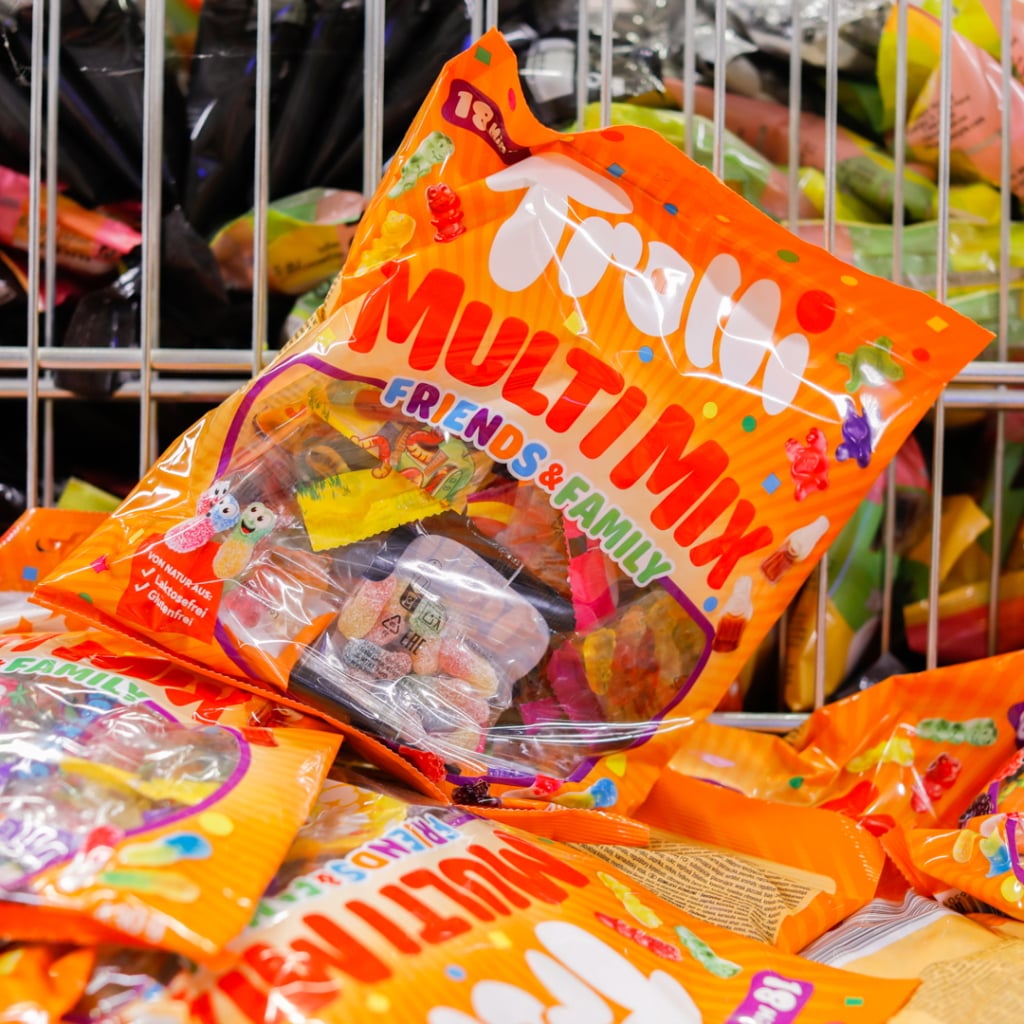 Förpackning med godiset "Trolli Multi Mix" som innehåller olika färgglada godisar för delning med vänner och familj, placerad i en butikshylla bland andra godispåsar.