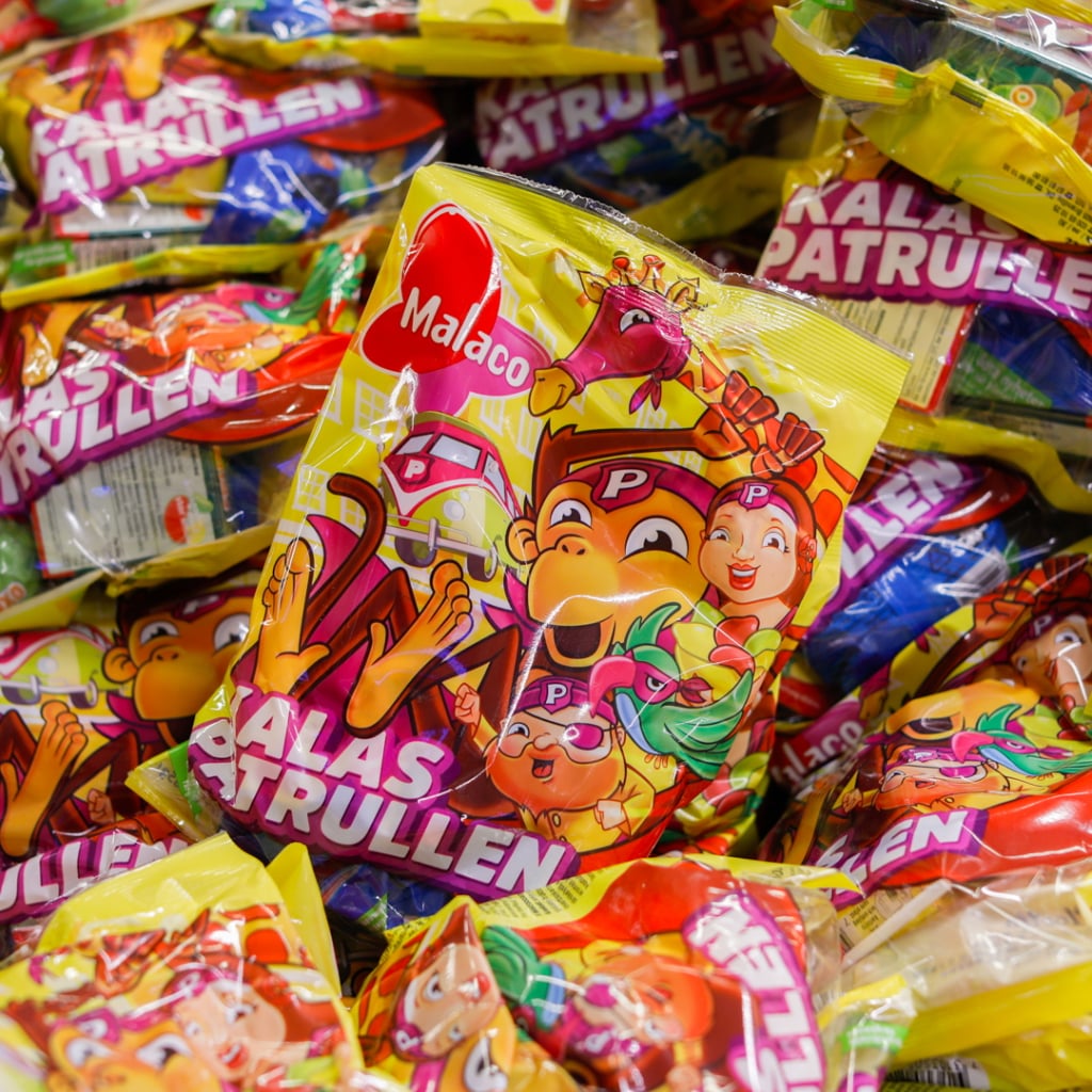 Förpackningar av Malacos godis "Kalaspatrullen" i en färgglad hög, med karaktärer och lekfull design som lockar barn.