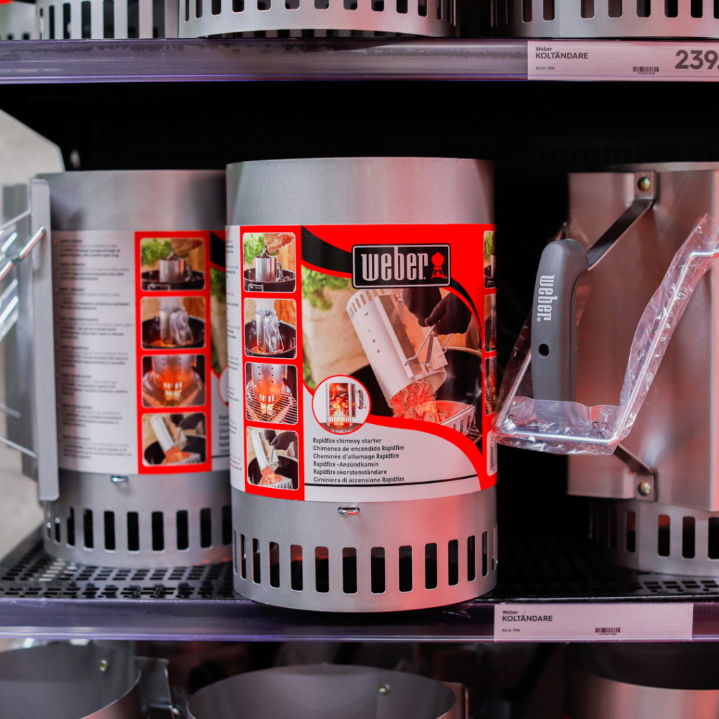 Weber kolstarter på hylla, med detaljerad förpackning som visar användning och funktioner. Perfekt för snabb och effektiv tändning av grillkol.